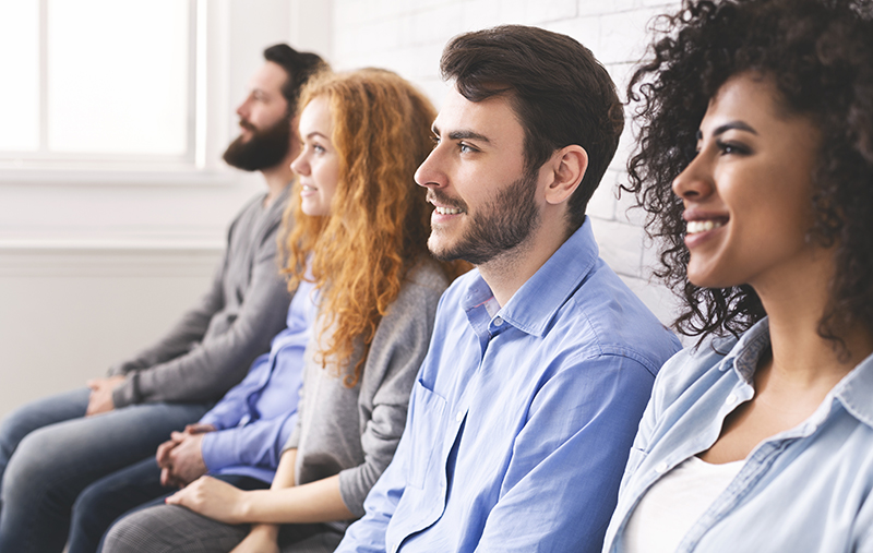 Multiethnic millennial people sitting in row and looking at speaker